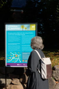 Person vor einer Infotafel des Lütauer Klimapfades