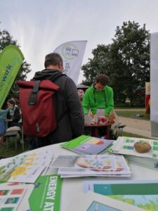 Christoph Thomsen von BobenOp führt an einem Infostand eine Bürgersolarberatung mit einem Besucher durch. Im Hintergrund ist eine Beachflag mit dem bewirk Logo, im Vordergrund ein Tisch mit Flyern zu sehen.